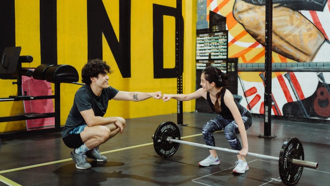 Man and woman in gym sharing a fist bump to celebrate a workout session.